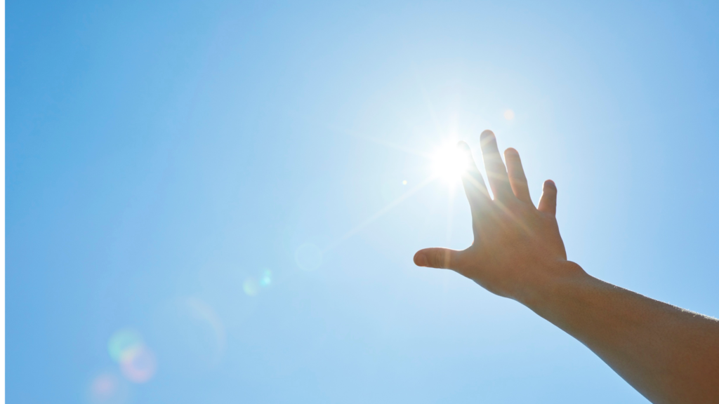 希望を感じさせる、太陽に手を伸ばす写真