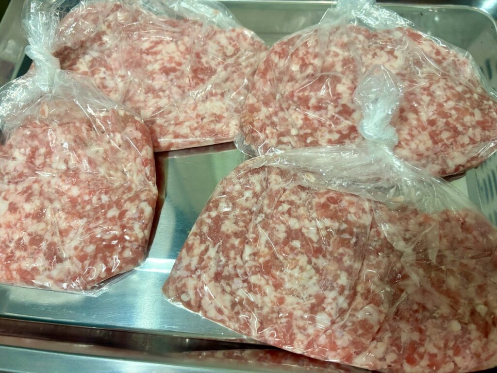 平らにしたひき肉4袋をステンレスのバットにのせたところ