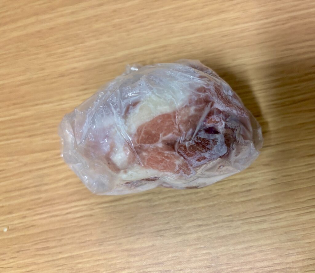 冷凍室の奥から出てきた豚肉。袋の内側に霜がつき、赤身が暗い色に変わっている