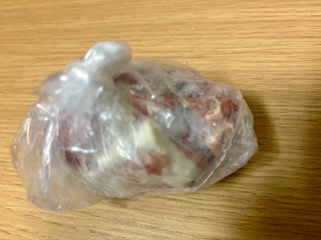 袋に入ったままの冷凍豚肉を別の角度から見たところ。白っぽい部分と暗い赤色の部分がある