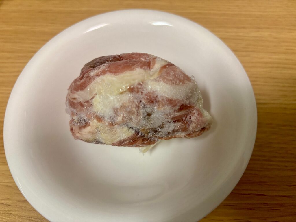袋から出した冷凍の豚こま肉。表面に霜が付き、一部が暗い赤茶色になっている