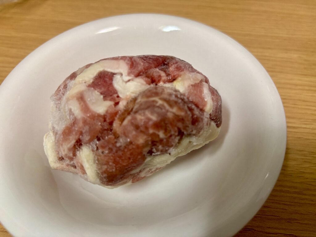 同じ冷凍の豚こま肉を別の角度から見たところ。クリーム色の脂身と暗い赤茶色の部分がある